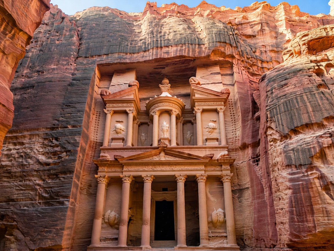 Al-Khazneh Treasury facade carved into pink rose sandstone rock canyon at Petra
